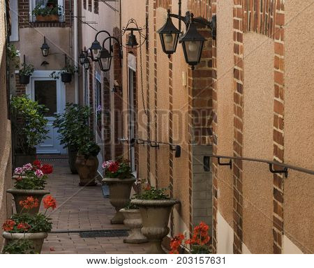Small alley in Hautvillers with geranium and lanterns in the Champagne district in France.