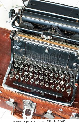 Old retro black metallic typewriter with antique round keys. Indoors closeup.