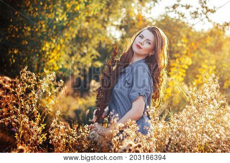 Young Woman With A Flowers In Autumn Field