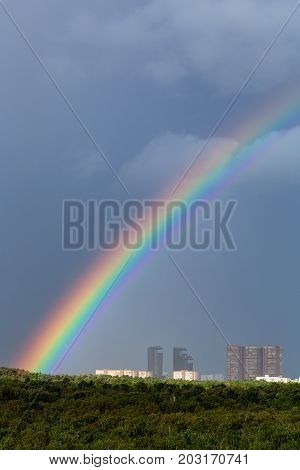 Rainbow In Rain Over City And Green Trees
