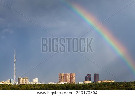 Sunbeams And Rainbow In Rainy Sky Over City