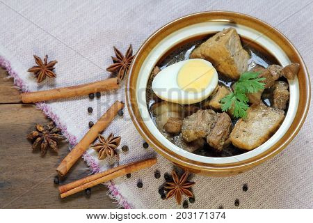 Belly Pork Chinese Five-Spice Stew with boiled egg and tofu in brown sauce decorated with anise star, black pepper and cinnamon, asia food.