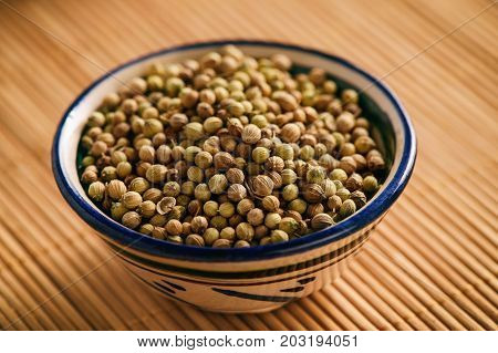 Coriander seeds, oriental spiсe, on brown background.