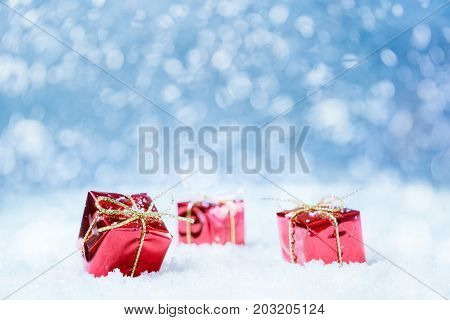 Red gifts on a snow with blue background for a greeting card or couponvoucher. Selected focus narrow depth of field.