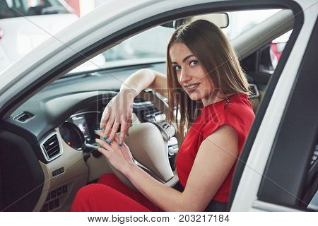 woman in car indoor keeps wheel turning around smiling looking at passengers in back seat idea taxi driver against sunset rays Light shine sky Concept of exam Vehicle - second home the girl.