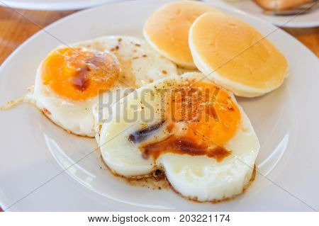 Fried Egg sprinkle with soy sauce and pepper with Pancake serve on dish.