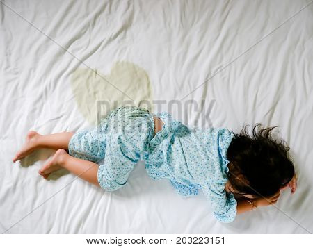 Child pee on a mattress, Little girl feet and pee in bed sheet, Child development concept , selected focus.