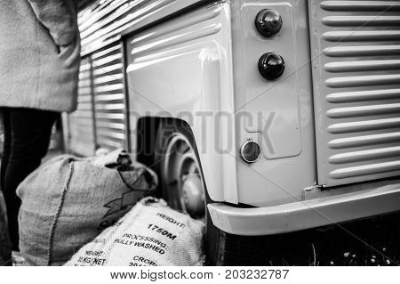 A oldtimer van with some sacks with coffee beans in it.