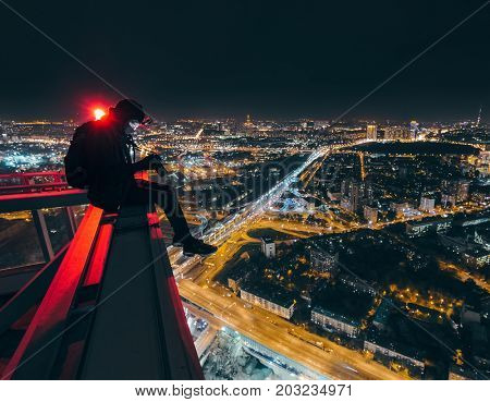 MOSCOS - OCT 17, 2015: Man sits with camera on skyscraper near beacon at night