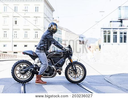 Motorcycle rider on custom made scrambler style cafe racer in the city