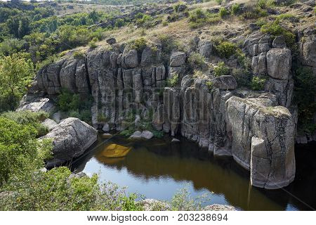 Increadibly beautiful lake in abandoned granite quarry as a background. Green magnificent nature. Colorful plants and trees on a stone canyon. Nature, summer, travel concept.