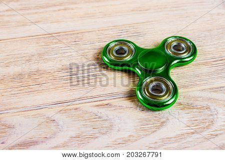 Green fidget spinner stress relieving toy on wood background