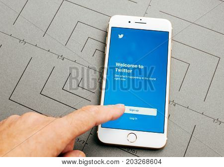 PARIS FRANCE - SEP 26 2016: Male hand holding New Apple iPhone 7 Plus after unboxing and testing by installing the app application software Twitter app sign in finger