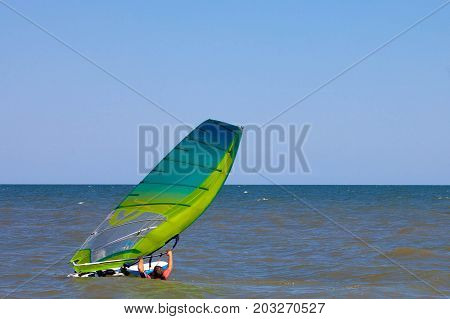 Windserfer learns beach start element with sail at sea ocean with free space