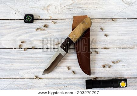 Knife, A Compass And A Flashlight On A White Wooden Background.