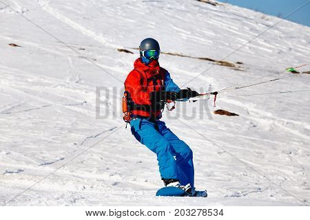 Snowboarder with a kite on fresh snow in the winter in the tundra of Russia against a clear blue sky. Teriberka, Kola Peninsula, Russia. Concept of winter sports snowkite.