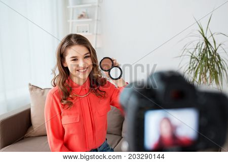 blogging, technology, videoblog, makeup and people concept - happy smiling woman or beauty blogger with bronzer and camera recording tutorial video at home