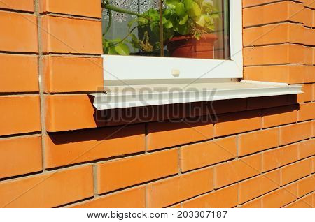 Close-up on single plastic window and metal sill detail. Install window against brick wall facade.