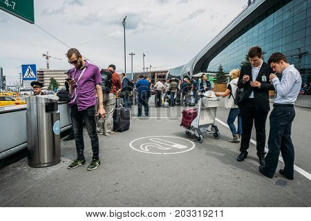Moscow, Domodedovo, Russia - May 29, 2017: People smoke in the area for smokers or smoking area at the entrance to the Domodedovo International Airport