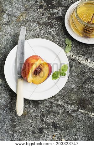 Juicy fresh nectarine on a white plate with a vintage silver knife on a gray stone background. Top View