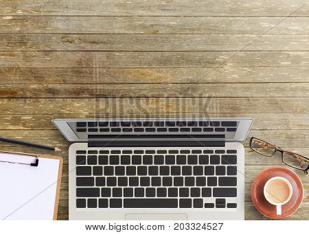 Office desk-top view of brown wooden office table with cup of coffeeglassespencil and notepad. working office space. office objects on the table. office working and business concept