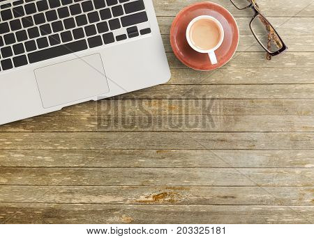 Office desk - Top view of brown wooden office table with cup of coffeeglassespencil and notepad. working office space. objects on the table. office working and business concept