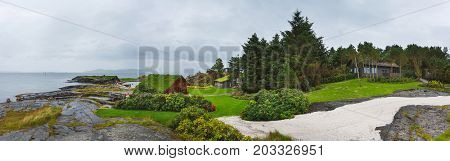 Stavanger Norway - August 28 2017: Panoramic view of wooden houses on the stony shore in Flor and Flaere garden in inclement weather