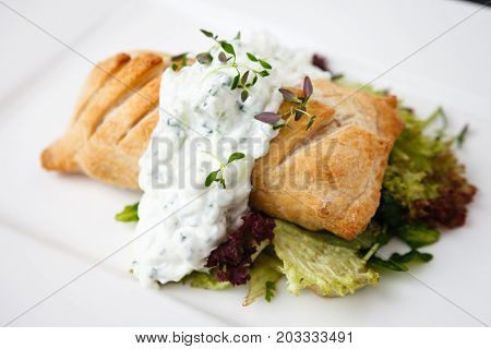 Traditional russian pie - coulibiac. Baked puff pastry filled with smoked salmon, served with sour cream sauce