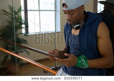 Young male dancer using digital tablet by mirror in studio