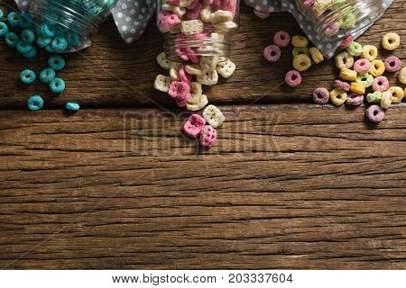 Overhead view of scattered honeycomb cereals from jar on wooden table