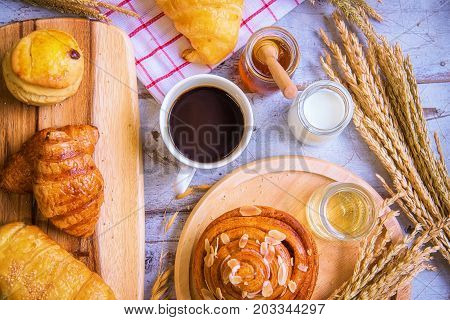 Fresh tasty bread with coffee and honey bee with milk on the table.