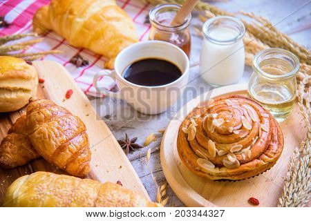 Fresh tasty bread with coffee and honey bee with milk on the table.