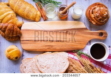 Fresh tasty bread with coffee and honey bee with milk on the table.