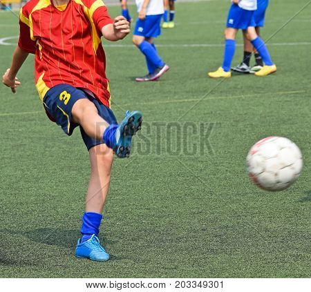 Young female soccer player kicks the ball