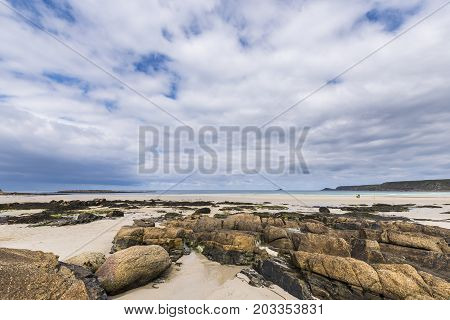 Sennen England - April 27 2017: Rocks at the Sennen Cove beach in Cornwall England wit a small island in the far distance.