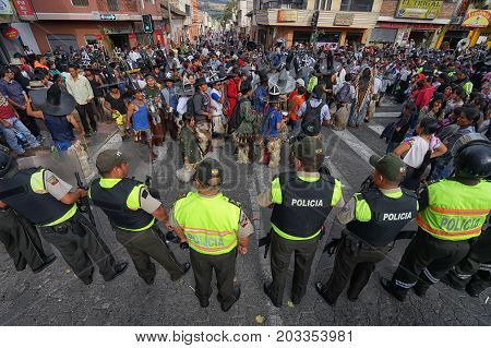 June 29 2017 Cotacachi Ecuador: police watching kichwa indigenous men dancing in the town plaza at Inti Raymi