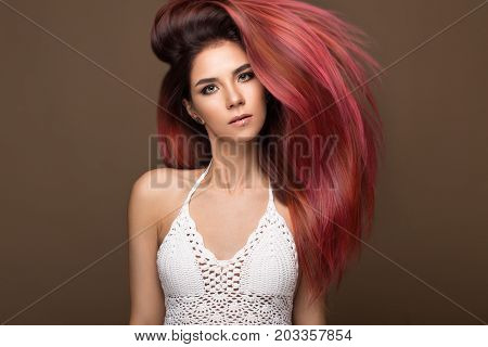 Beautiful pink-haired girl in move with a perfectly smooth hair, and classic make-up. Beauty face. Picture taken in the studio.