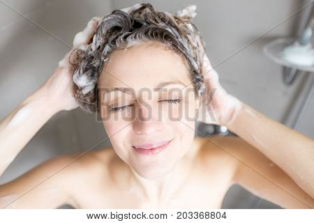 A beautiful Woman in shower washing hair with shampoo