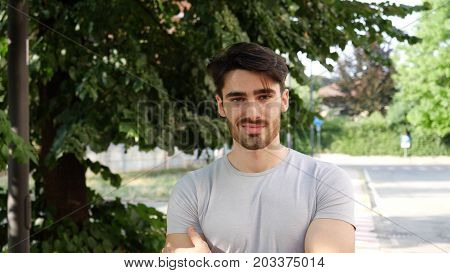 Handsome young man outdoor looking around and at camera with arms crossed on chest