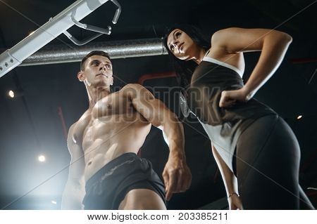 Handsome young muscular Caucasian man and woman working out training in the gym gaining weight pumping up muscles and poses fitness and bodybuilding concept