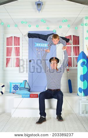 MOSCOW - OCT 04, 2016: Father (with model release) in cap with inscription Pacific Fleet with son (with model release) in vests perform acrobatic support at arms on porch of the white house with door
