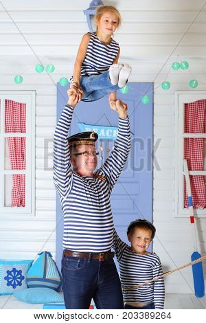 MOSCOW - OCT 04, 2016: Father (with model release) in cap with inscription with daughter (with model release) perform acrobatic support at arms near son (with model release) in front of the lilac door