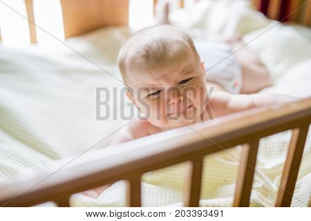 A Close-up portrait of a crying cute baby in the crib at home