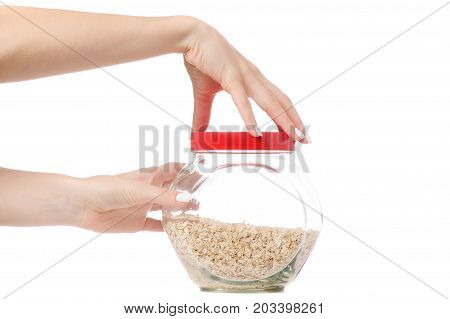 Female hand capacity with a lid of flakes of oats on a white background isolation