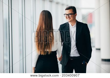 Businessman And Businesswoman Shaking Hands In Office With Big Panoramic Windows In Office Hall