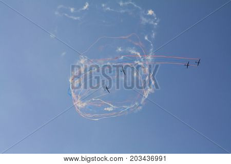 Beautiful acrobatics show of a group of gliders in a sunny sky. Draw colorful loops in the sky.
