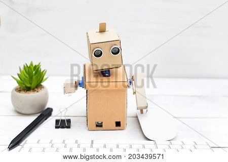 robot works behind a white keyboard next to a flower stands sacculent