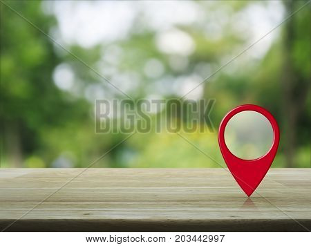Map pin location button on wooden table over blur green tree in park Map pointer navigation concept