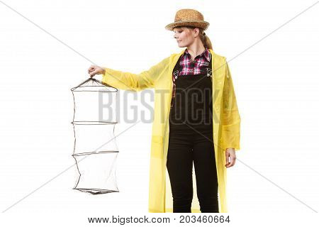Spinning angling cheerful fisherwoman concept. Happy woman in yellow raincoat holding empty fishing keepnet having fun.