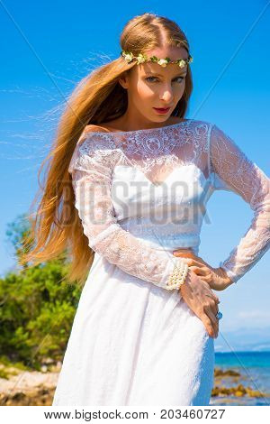 A young beautiful woman standing at the ocean in the summer.